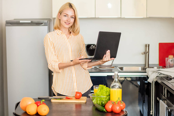 Woman using laptop in the kitchen - Fotó, kép