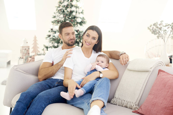 Lovely family with their baby girl relaxing on sofa at home duri - Foto, Imagem