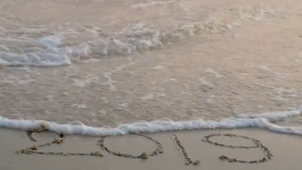 4k. šťastný nový rok 2020. číslo 2019 psát na písčité pláži, vlna splash změna na 2020. odpočet pro šťastný nový rok otáčení od roku 2019 do roku 2020 - Záběry, video