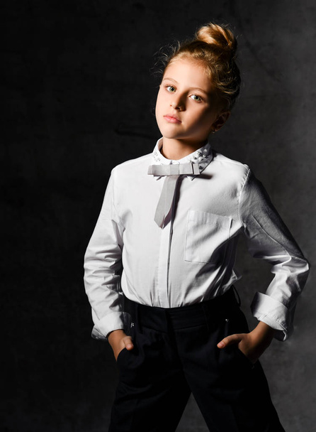 Little female caucasian model posing in school uniform on a gray concrete studio background. - Fotografie, Obrázek