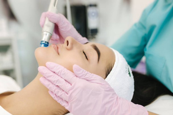 Detailní záběr ženy podstupující léčbu peeling hydromikrodermabrazí obličeje. Žena v kosmetických kosmetických lázních slinic. Hydra vysavač. Kosmetologie - Fotografie, Obrázek