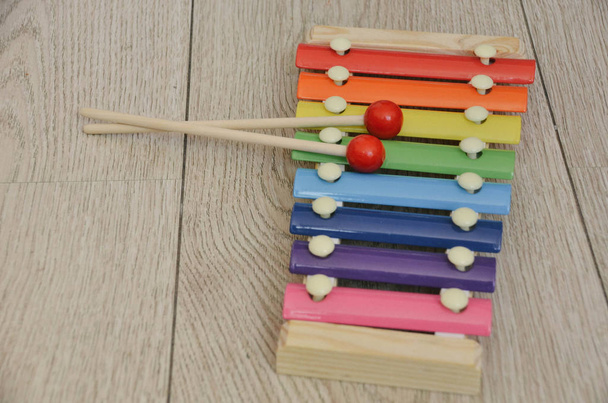 Xilofone colorido brilhante com varas vermelhas fechar em fundo de madeira. Instrumento musical Montessori
 - Foto, Imagem