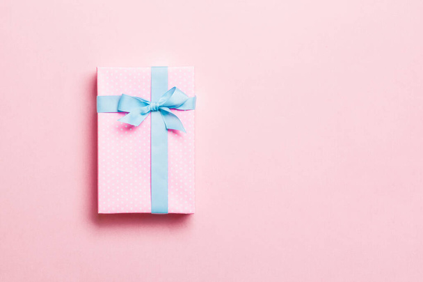 Gift box with blue bow for Christmas or New Year day on pink background, top view with copy space - Photo, Image