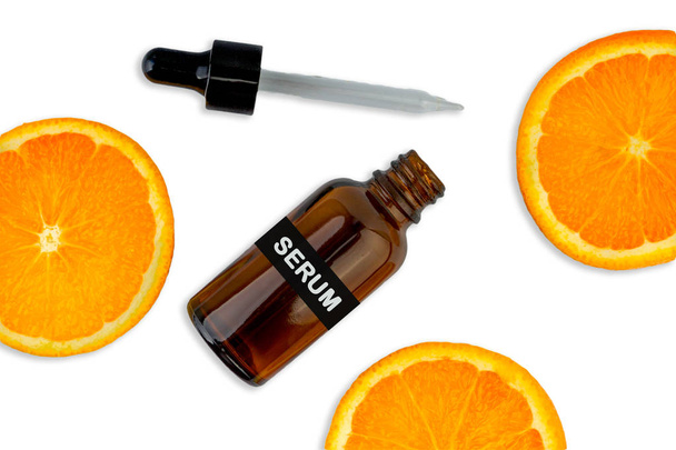 Kozmetik şişesinde C vitamini serumu, beyaz arka planda dilimlenmiş portakal. Sağlık hizmeti kavramı - Fotoğraf, Görsel