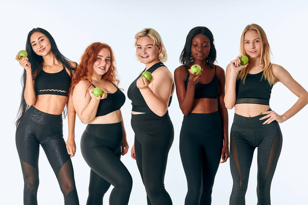 Healthy lifestyle concept. Portrait of girls eating green apple - Foto, Imagem