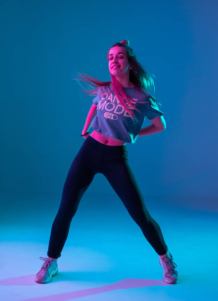 Young stylish girl dancing zumba in the Studio on a colored neon background. Dance poster design. - Photo, Image