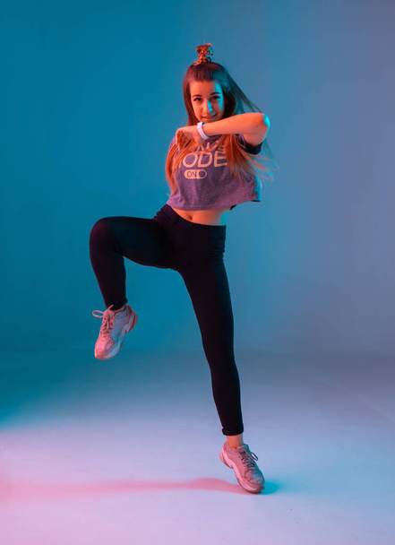 Young stylish girl dancing zumba in the Studio on a colored neon background. Dance poster design. - Foto, imagen