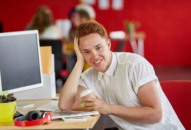 Αυτοπεποίθηση αρσενικό σχεδιαστή έχοντας έναν καφέ στη δουλειά σε κόκκινο δημιουργικό - Φωτογραφία, εικόνα