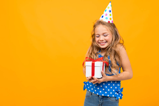 little smart girl posing with gift against orange background   - Фото, зображення