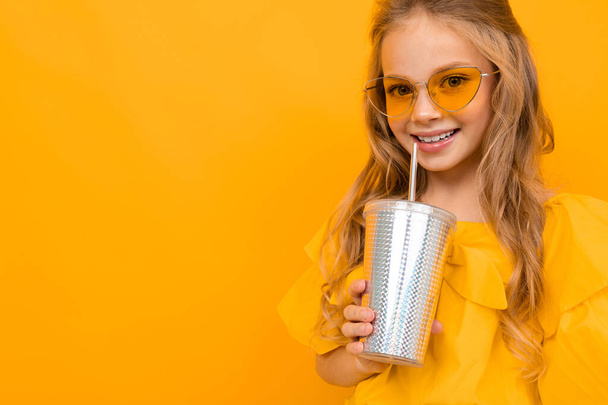 Nettes kleines Mädchen posiert mit Papierglas vor orangefarbenem Hintergrund  - Foto, Bild