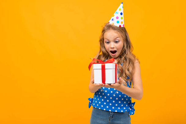 piccola ragazza intelligente in posa con regalo contro sfondo arancione
   - Foto, immagini