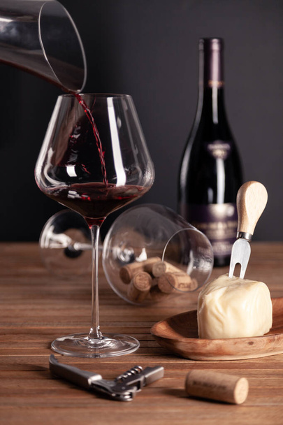 Giet rode wijn in kristalglas, fles, kurkentrekker, opener, dus - Foto, afbeelding