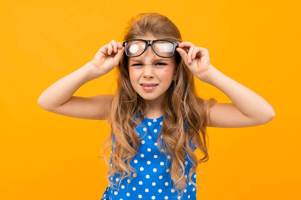 malá chytrá dívka pózuje s brýlemi proti oranžovému pozadí   - Fotografie, Obrázek