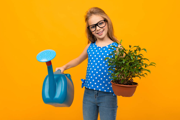маленька дівчинка позує з поливом і вазоном на помаранчевому фоні
  - Фото, зображення