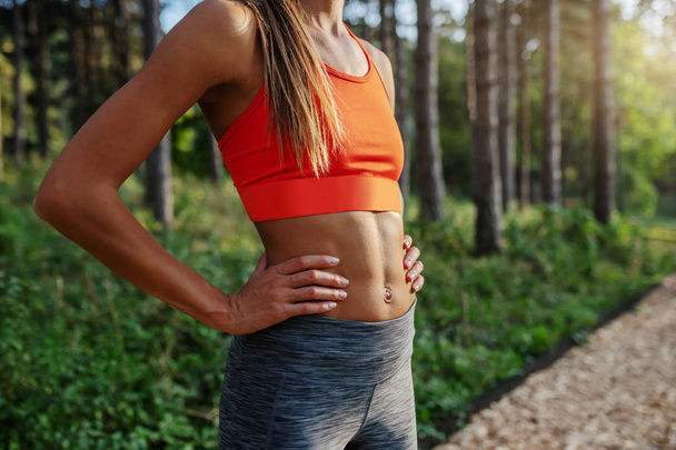 Zdravá štíhlá bělošská brunetka ve sportovním oblečení stojící na stezce v lese s pažemi na bocích. - Fotografie, Obrázek