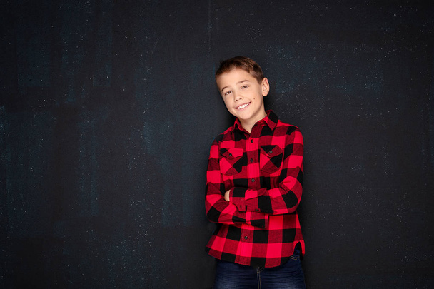 Teenage boy in checkered shirt over black chalk board. - Fotó, kép