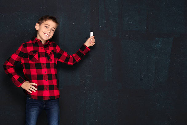 Teenage boy in checkered shirt over black chalk board. - Foto, imagen