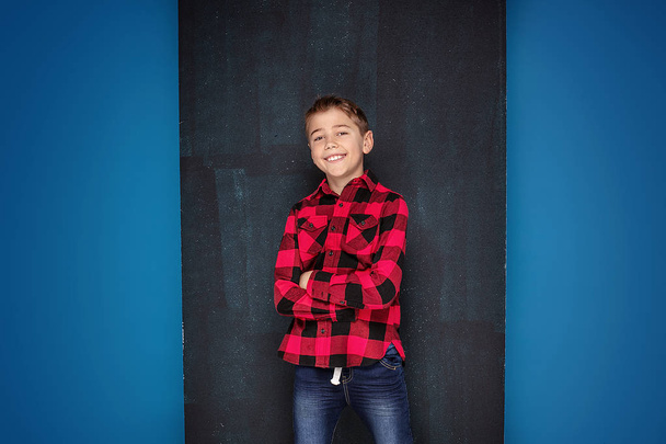 Teenage boy in checkered shirt over black chalk board. - Zdjęcie, obraz
