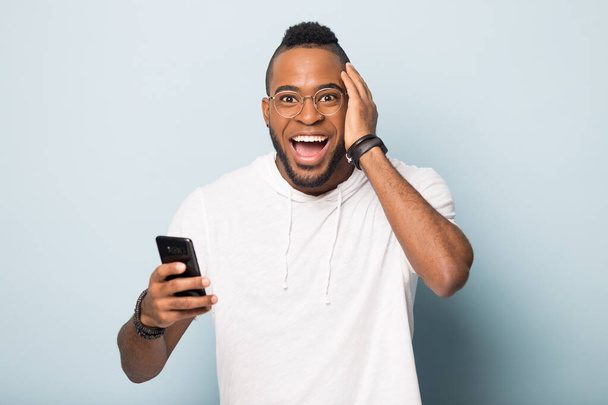 Alegre afroamericano hombre sorprendido por la victoria en línea del teléfono celular
 - Foto, Imagen