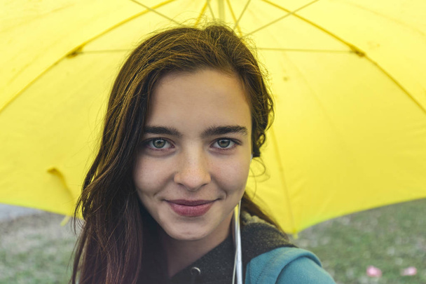 retrato de una joven sonriente con paraguas amarillo
 - Foto, Imagen