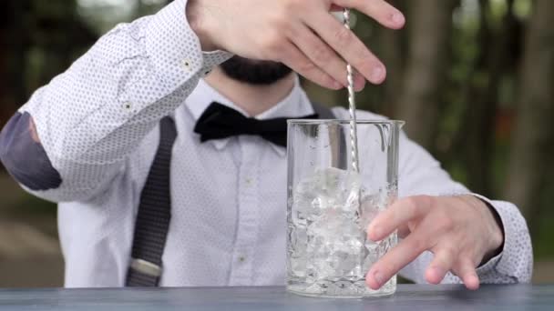 бармен размешивает ложку для мороженого на прилавке, стакан со льдом крупным планом, бармен делает охлаждающий напиток на свежем воздухе, работает в баре
 - Кадры, видео