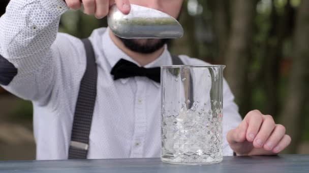 bartender na mesa de bar colocar cubos de gelo claros em vidro, barman colocar gelo em vidro no ar fresco, trabalhador bar prepara bebida alcoólica, serviço evento
, - Filmagem, Vídeo
