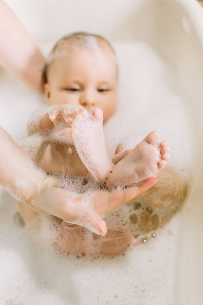 Happy little baby a swimming in the bathroom.Portrait of baby bathing in a bath with foam - Фото, зображення