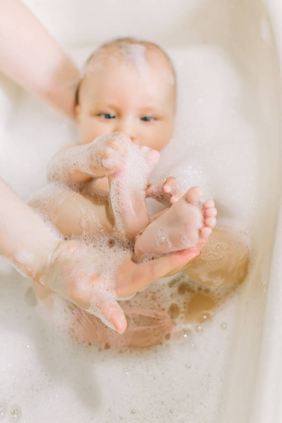 Happy little baby a swimming in the bathroom.Portrait of baby bathing in a bath with foam - Фото, зображення