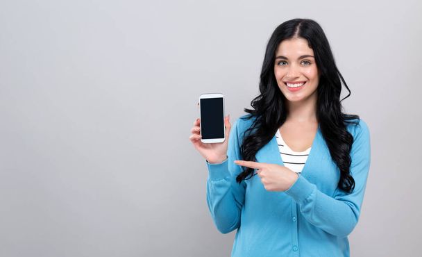 Jeune femme tenant un téléphone dans sa main
 - Photo, image