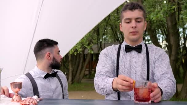 barman zdobený citrusovým koktejlem pro zákazníka, barman za barem, barman dělá studený nápoj ve skle - Záběry, video