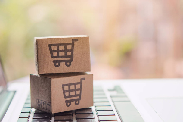 Online vásárlás - Papírdobozok vagy csomagok bevásárlókosár logóval egy laptop billentyűzeten. Bevásárlási szolgáltatás az online weben, és kínál házhozszállítás - Fotó, kép