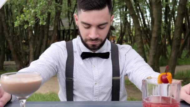 barman za barem na pozadí parku, barman close-up, barman předložit alkohol, barevné chlazené nápoje na baru pultu - Záběry, video