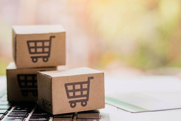 Online shopping - Paper cartons or parcel with a shopping cart logo and credit card on a laptop keyboard. Shopping service on The online web and offers home delivery. - Zdjęcie, obraz