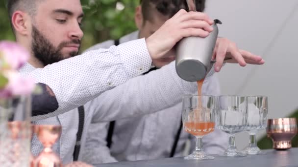 bartender fills wineglass with ice liqueur, barman uses mixing glass and strainer, barkeeper makes colour cocktail - Footage, Video
