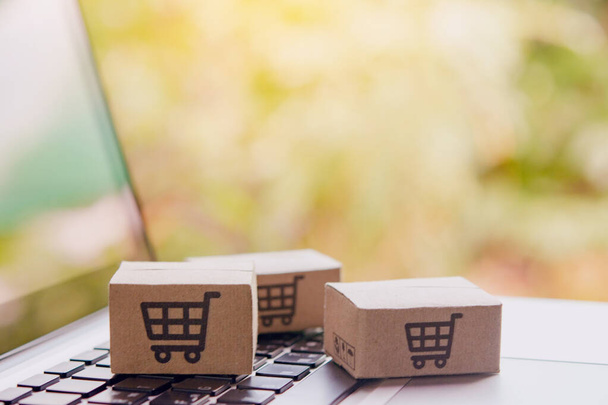 Online vásárlás - Papírdobozok vagy csomagok bevásárlókosár logóval egy laptop billentyűzeten. Bevásárlási szolgáltatás az online weben, és kínál házhozszállítás - Fotó, kép