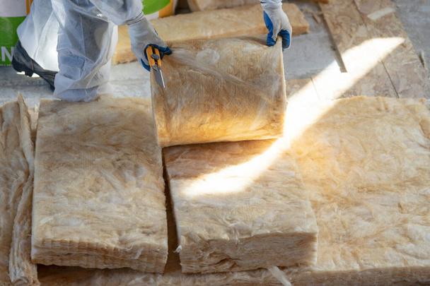 Professional foreman installing thermal insulation rock wool under the roof - Photo, Image