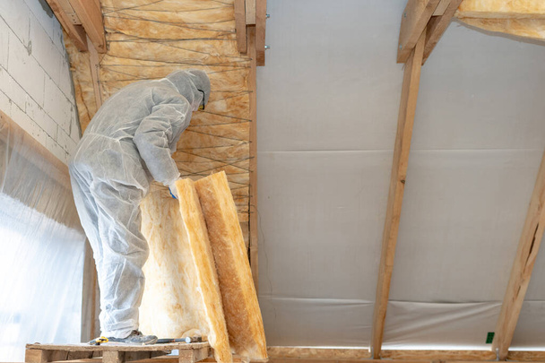 Profesjonalny pracownik instalujący warstwę izolacji termicznej z wełny mineralnej - Zdjęcie, obraz