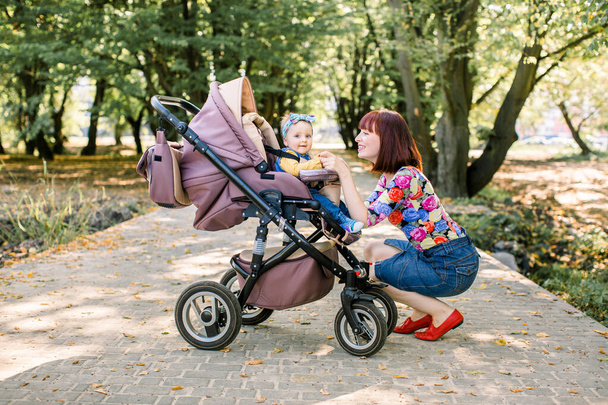 Young mother looking at her child in a baby stroller - Foto, immagini
