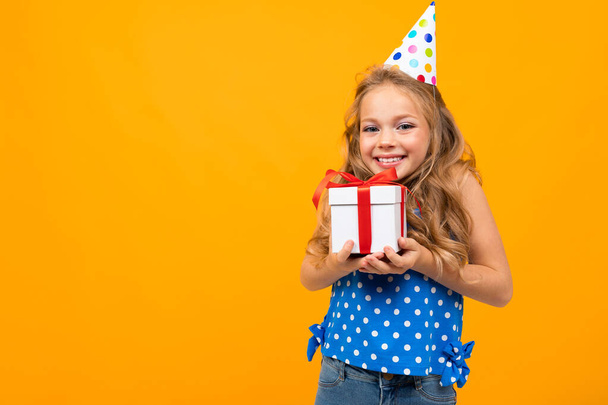 kleines smartes Mädchen posiert mit Geschenk vor orangefarbenem Hintergrund   - Foto, Bild