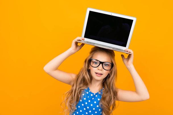 маленька дівчинка позує в окулярах і ноутбуці на помаранчевому фоні
  - Фото, зображення