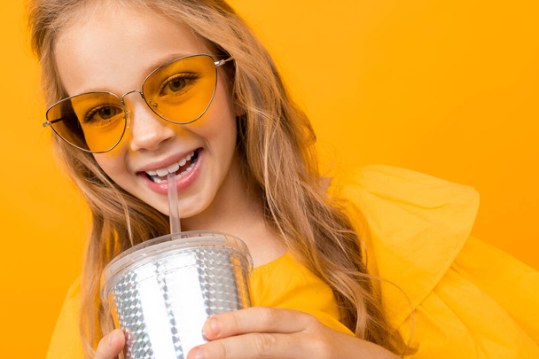 aranyos kislány pózol papír üveg ellen narancs háttér  - Fotó, kép