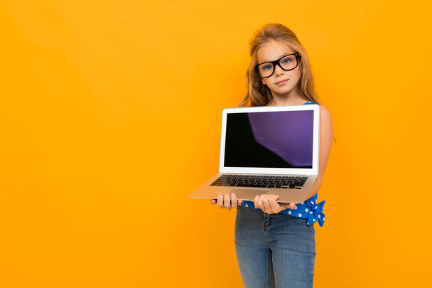 little girl posing with glasses and laptop against orange background  - Valokuva, kuva