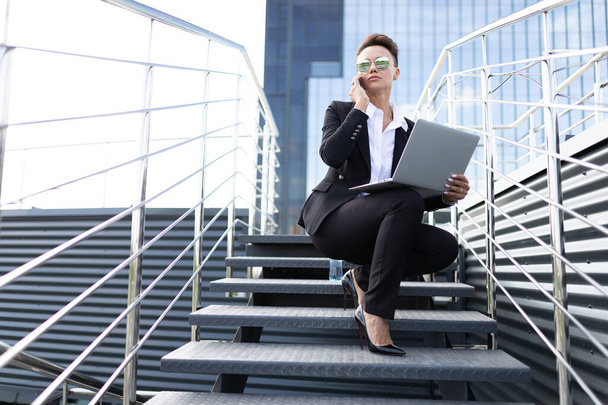 outdoor portrait of young beautiful business woman with phone and laptop - Foto, Imagen