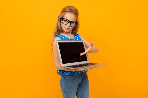 kislány pózol szemüveg és laptop narancssárga háttér  - Fotó, kép