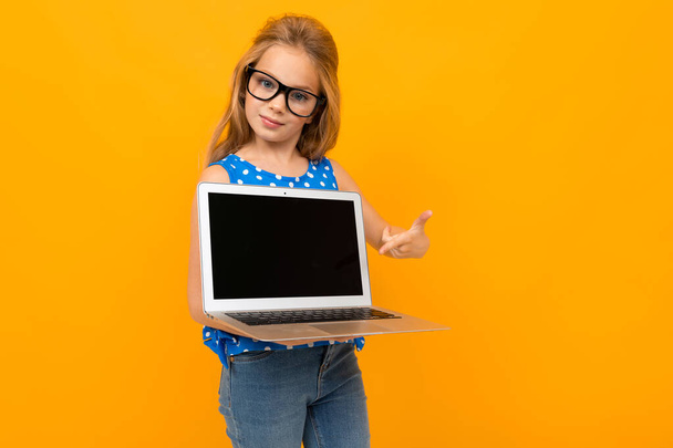 маленькая девочка позирует в очках и ноутбуке на оранжевом фоне
  - Фото, изображение