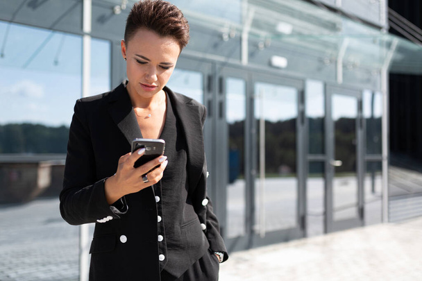 красивая деловая женщина позирует на открытом воздухе с телефоном
 - Фото, изображение