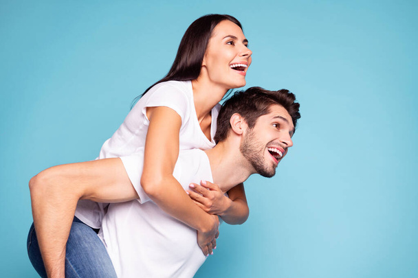 Close-up profile side view portrait of his he her she nice attractive lovely cheerful cheery couple piggybacking having fun isolated on bright vivid shine vibrant blue turquoise background - Foto, imagen