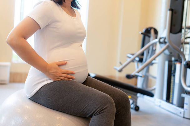 Ejercicio activo de mujer embarazada en el gimnasio. - Foto, imagen
