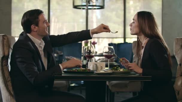 Romantic couple eating at restaurant. Man give food to woman at romantic dinner - Video