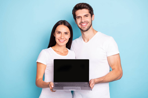 Close-up portrait of his he her she nice attractive cheerful cheery couple holding in hands showing laptop screen new digital product isolated on bright vivid shine vibrant blue turquoise background - Foto, afbeelding